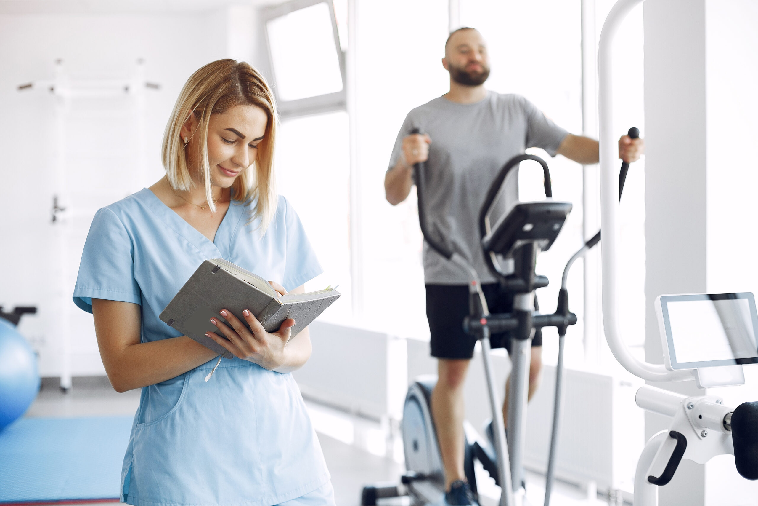 A woman is a physiotherapist. A man is using a spin bike. The patient is having a treatment.